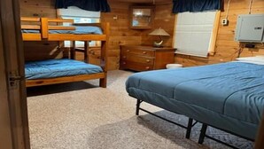 A wooden cabin bedroom with bunk beds, a dresser, and a lamp. - 2 Bedroom Riverside Cabin (The Forks)
