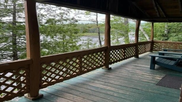 A covered outdoor area with wooden benches and lattice railings. - 2 Bedroom Riverside Cabin (The Forks)