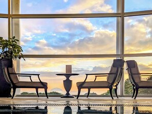 A room with a large window, two chairs, a small table, and a potted plant.