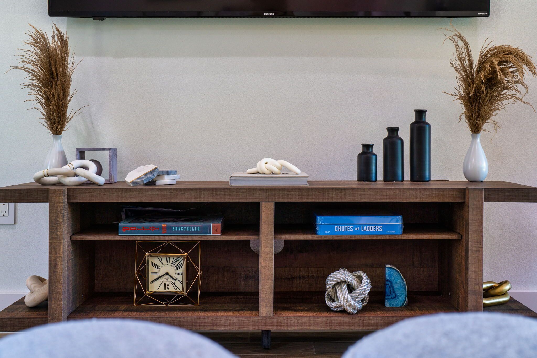 Een houten console tafel met decoratieve objecten, boeken en een klok.