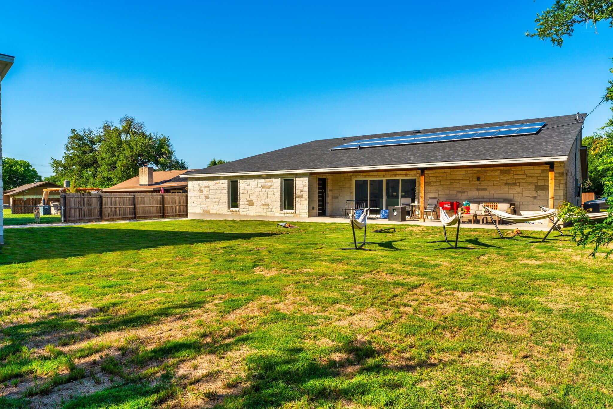 A two-story house with a stone facade, a large garage, and a covered patio area.