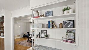 Una cocina moderna con armarios blancos, encimeras de mármol y vista al comedor.