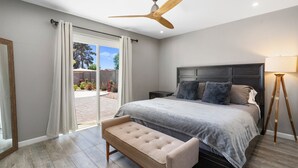 A bedroom with a large bed, a bench, a ceiling fan, and a view of the outdoors. - Sparkling Pool  Putting Green in Tempe (Tempe)