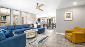 A modern living room with a blue sectional sofa, a yellow armchair, and a dining area in the background. - Sparkling Pool  Putting Green in Tempe (Tempe)
