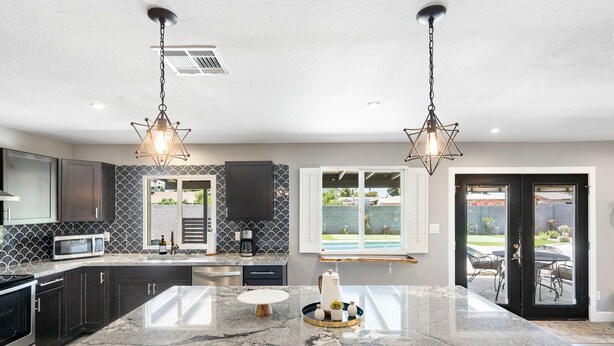 A modern kitchen with a large island, black cabinets, a microwave, and a sink. - Sparkling Pool  Putting Green in Tempe (Tempe)