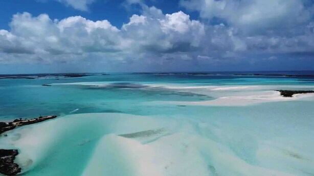 Un paisaje costero con aguas turquesas cristalinas y un litoral rocoso.