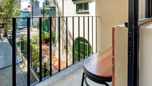Ein Balkon mit Blick auf eine Straße, einem grünen Tor und einem Blumentopf.