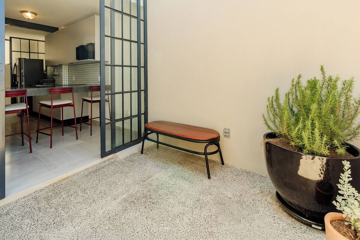 A modern kitchen with a dining area, a bench, and a large potted plant.