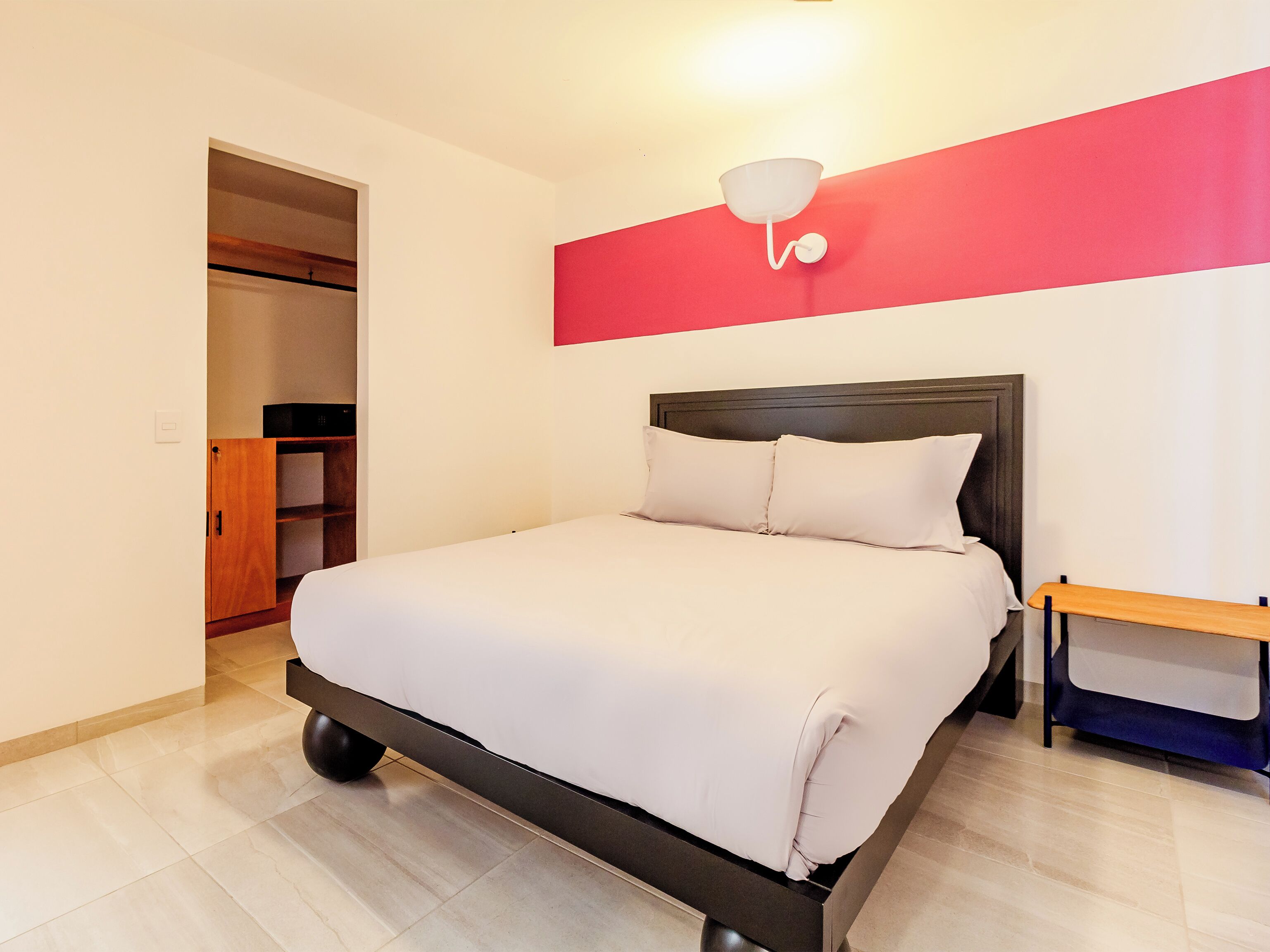 A neatly arranged bedroom with a bed, a wardrobe, and a bedside table.