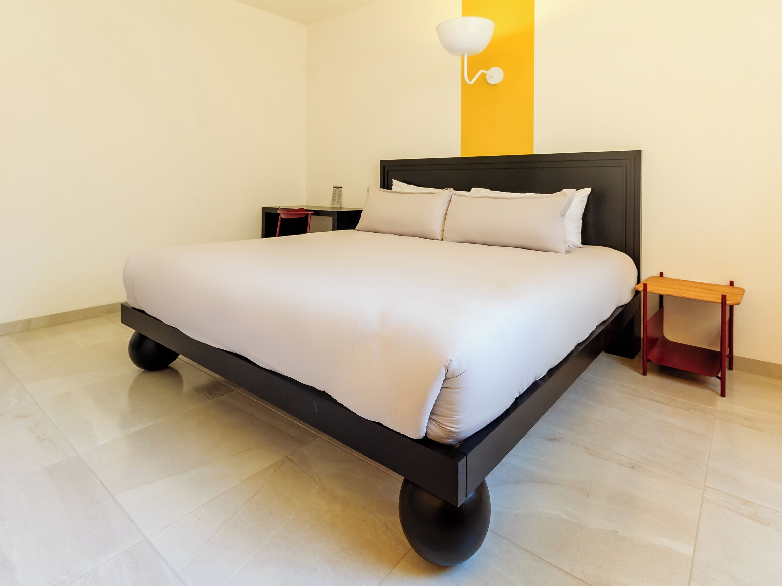 Een moderne hotelkamer met een groot bed, een nachtkastje en een wandlamp.