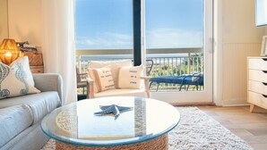 A living room with a glass coffee table, a sofa, and a view of the balcony. - Oceanfront Villa with Pool (Hilton Head Island)