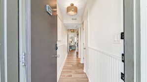 A hallway with a wooden floor, white walls, and a ceiling light fixture. - Oceanfront Villa with Pool (Hilton Head Island)