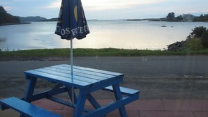 A blue picnic table with an umbrella labeled "TOS FO'ELL" by the water. - Erisgeir Sleeps 6 With Private Grounds (Isle of Mull)