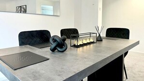 Μια αίθουσα συνεδριάσεων με ένα μεγάλο τραπέζι, μαύρες καρέκλες με επένδυση, μια γυάλινη βάση για κεριά και ένα μαύρο βιβλίο πάνω στο τραπέζι.
