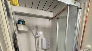 Ein gläserner Duschbereich mit weiß geflieste Wand, einer Handbrause und einer Bedienkonsole.