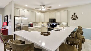 Una cocina moderna con gabinetes blancos, electrodomésticos de acero inoxidable y una isla grande con asientos.