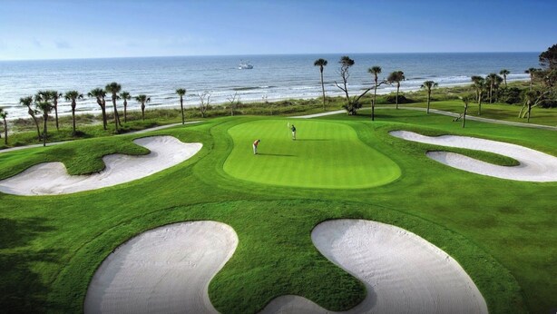Un campo de golf con vista al océano y palmeras.
