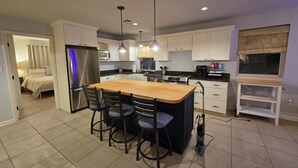 A modern kitchen with a central island, bar stools, and pendant lighting.