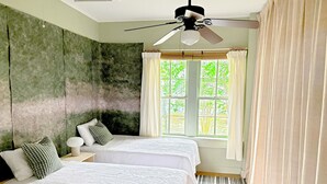 A bedroom with two beds, a ceiling fan, a window with curtains, and a view of greenery outside. - Charming Home 2 miles to UGA (Athens)