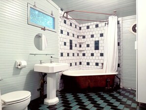 Une salle de bain avec des toilettes blanches, un lavabo sur colonne, une baignoire et un rideau de douche.