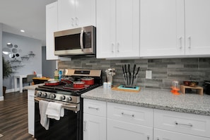 A modern kitchen with white cabinets, a stainless steel microwave, a gas stove, and granite countertops. - Cozy Retreat Near NRG Stadium, Free parking, Wi Fi  (Houston)