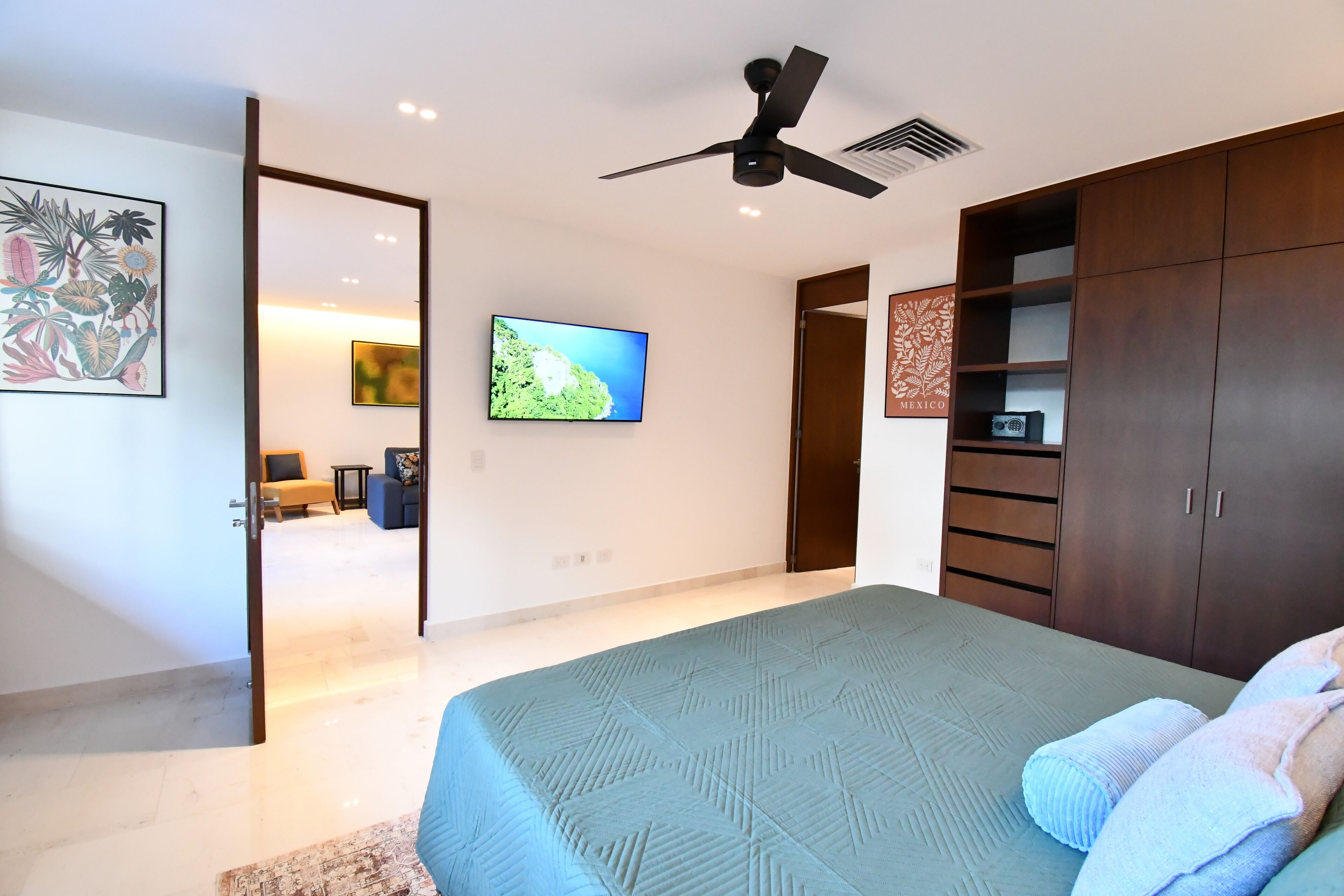 Quarto com cama, ventilador de teto, televisão e guarda-roupa.
