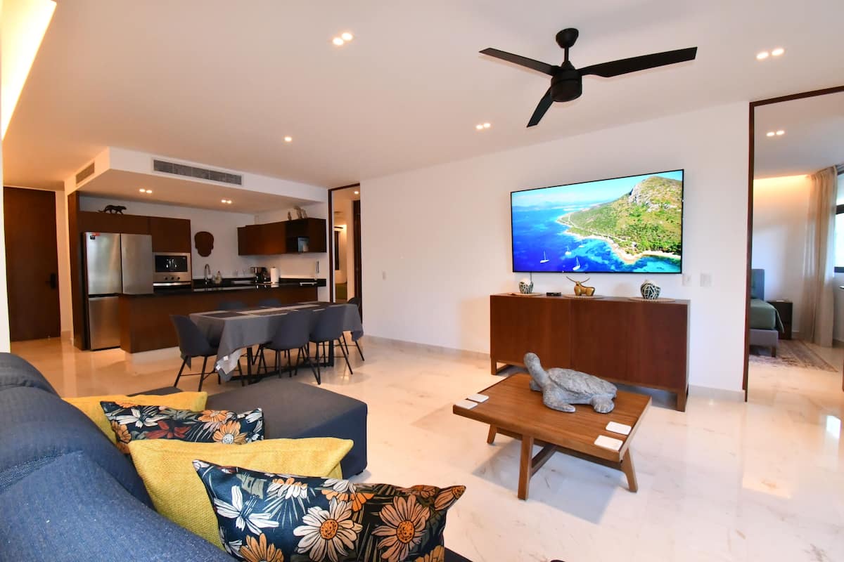 A modern living room with a sofa, coffee table, and a TV mounted on the wall.