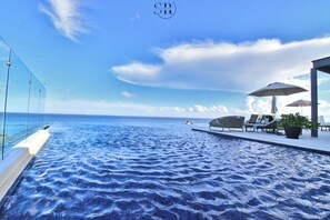 A infinity pool with a view of the ocean, lounge chairs, and umbrellas. - Marila Condos by The Spot Rentals (Playa del Carmen)