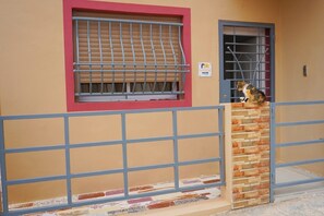 A building with a beige exterior, a red window frame, and a metal gate.