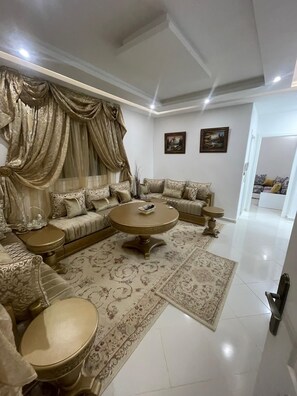 A spacious living room with a large sofa set, a coffee table, and a patterned rug.