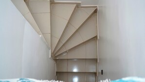 A room with a unique geometric staircase design, white walls, and a blue bedspread. - Furnished MinVilla (duplex)  (Ouad-Eddahab Dakhla)