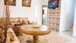 A living room with a round coffee table, a sofa, and a TV mounted on the wall. - Furnished MinVilla (duplex)  (Ouad-Eddahab Dakhla)