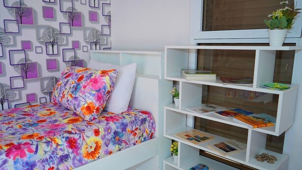 A bedroom with a bed, a bookshelf, and a wall with a geometric pattern. - Furnished MinVilla (duplex)  (Ouad-Eddahab Dakhla)
