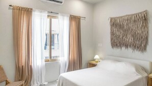 Et hotelværelse med en seng, en stol, et natbord med lampe og et billedværk på væggen.