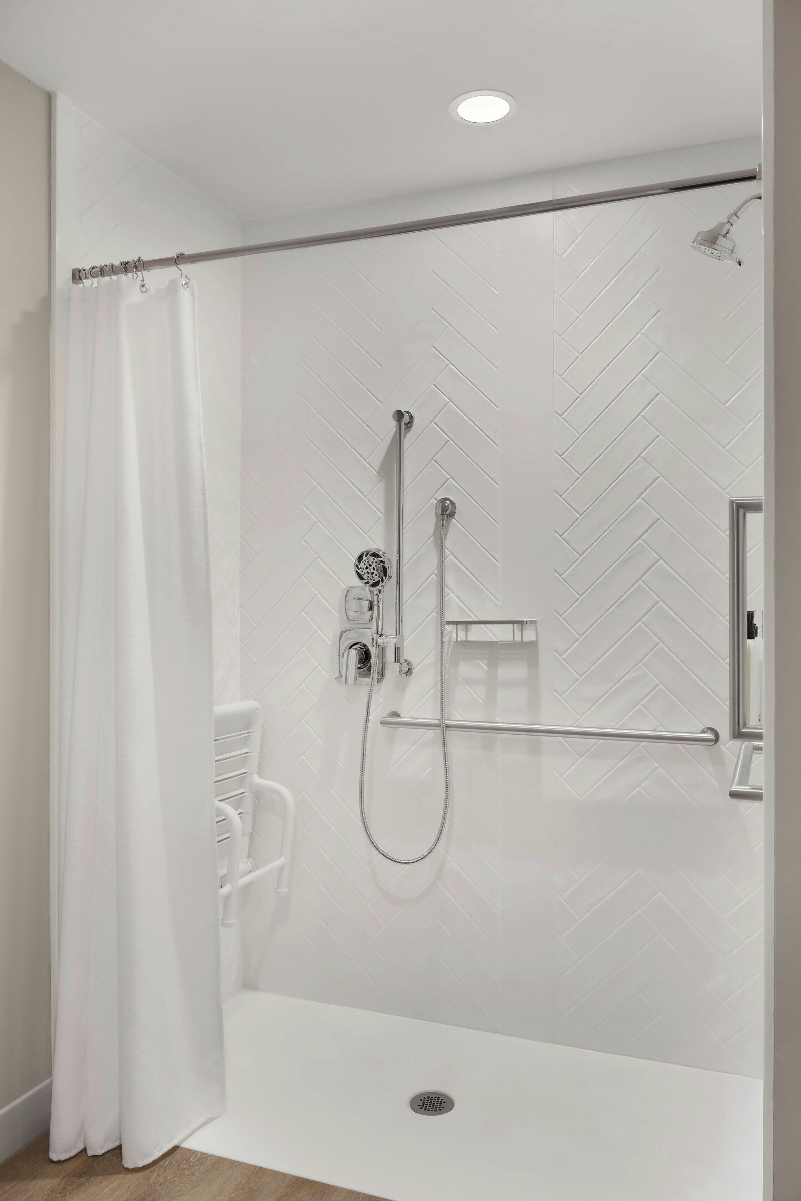 A modern shower area with a herringbone tile pattern, a handheld showerhead, and a glass-enclosed shower stall.