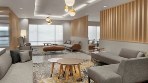 A modern hotel lobby with a sofa, armchairs, a coffee table, and pendant lighting. - Towneplace Suites By Marriott Crown Point (Crown Point)