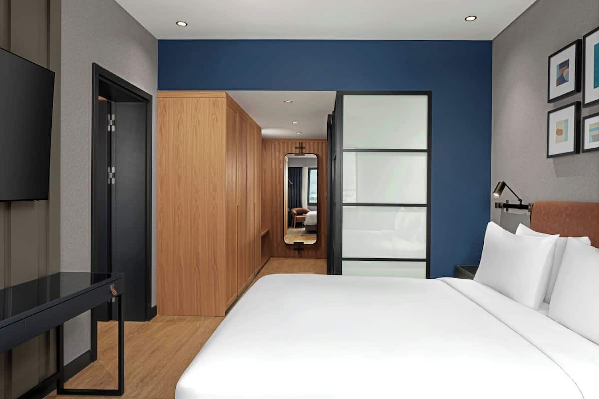 Une chambre d’hôtel moderne, dotée d’un grand lit, d’un bureau et d’une armoire.