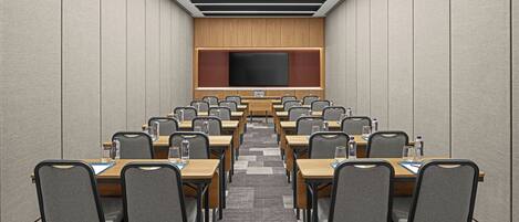 A conference room with a long table, multiple chairs, a large screen, and a wooden panel wall.