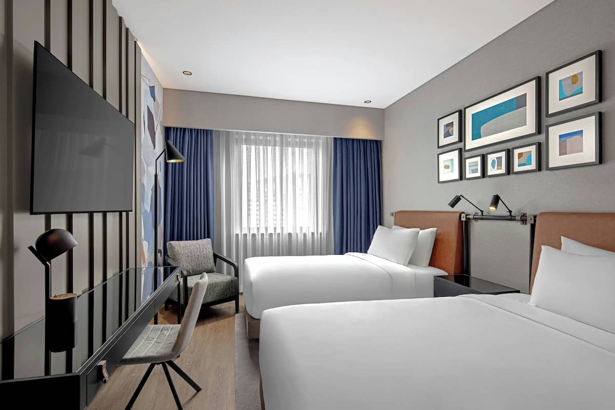 Une chambre d’hôtel avec deux lits, une télévision, un bureau et une chaise.
