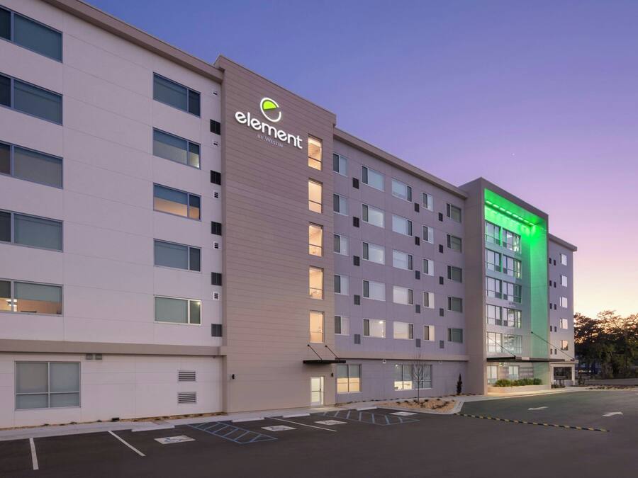A multi-story hotel with a prominent 'element by Westin' sign, featuring a modern facade with large windows and a parking lot in front.