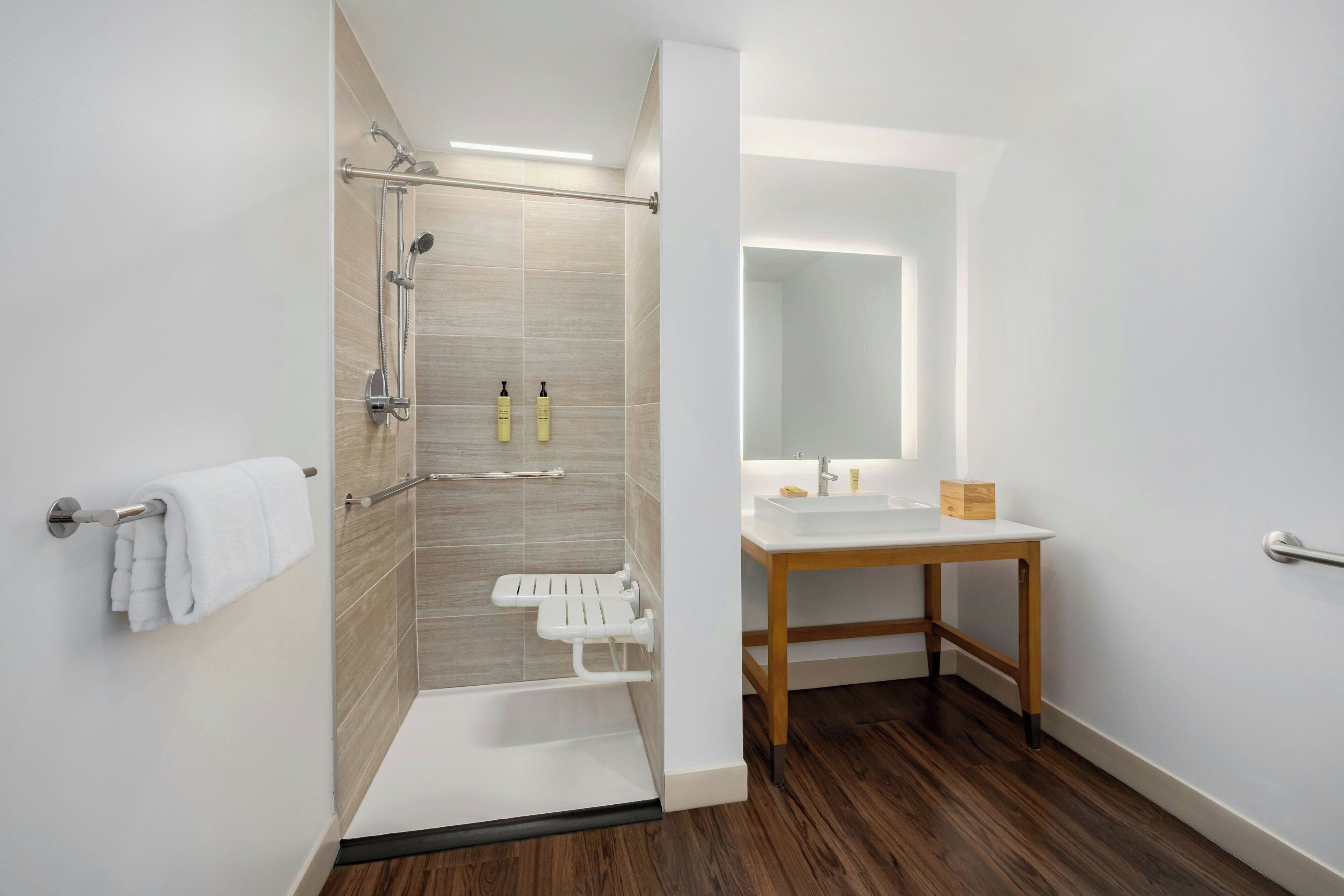 Une salle de bain moderne avec une douche, un lavabo et un miroir.