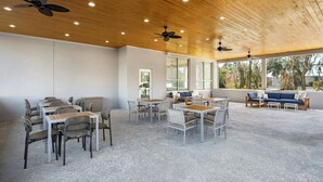 A spacious indoor area with tables and chairs, a sofa, and ceiling fans. - Element by Marriott Savannah Midtown (Savannah)
