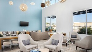 A modern living room with a blue accent wall, a flat-screen TV, and a large window offering a view of the outdoors. - Element by Marriott Savannah Midtown (Savannah)
