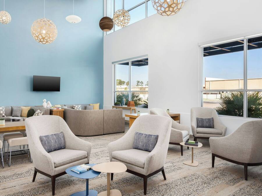 Una sala de estar moderna con una pared de acento azul, un televisor de pantalla plana y un ventanal con vistas al exterior.
