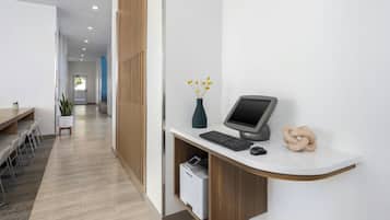 A modern reception desk with a computer, a vase with yellow flowers, and a printer.