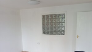 A room with a wooden floor, a white table with two chairs, a decorative window, and a white door. - Cosy London Apartment Retreat - Colindale (London)