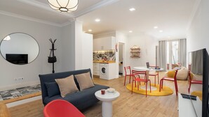 Ein modernes Wohnzimmer mit einer Couch, einem roten Sessel und einem Essbereich mit Tisch und Stühlen.