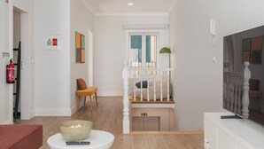 Un salon moderne avec un escalier, un téléviseur, un extincteur et un bol de pop-corn posé sur une table.