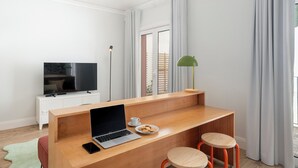 Une pièce moderne et minimaliste, avec un bureau en bois, un ordinateur portable, une assiette de biscuits et deux tabourets.