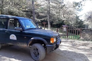 A black SUV parked on a dirt path with a wooden fence and a stone wall in the background. - La tua vacanza in montagna nel Parco dei Nebrodi (CESARO')